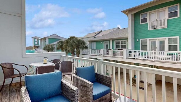 A balcony with wicker furniture and a view of neighboring houses. - Shared Pool and Hot Tub, Golf Cart Access (Port Aransas)