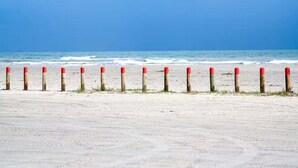 A beach with a row of wooden posts capped with red and white. - Shared Pool and Hot Tub, Golf Cart Access (Port Aransas)