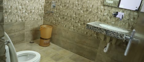 Casa de banho com parede em mosaico, sanita, lavatório com bancada de mármore e um contentor de lixo.