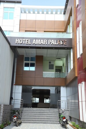 The entrance to Hotel Amar Palace with a modern facade, a staircase leading to the entrance, and two motorcycles parked outside. - Hotel amar Palace (Bharatpur)