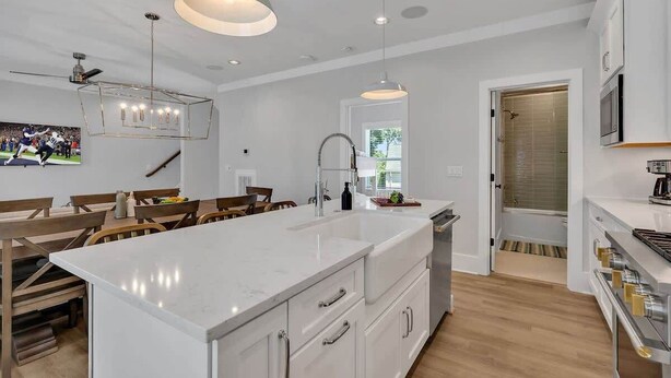 A modern kitchen with a large island, pendant lighting, and a dining area with wooden furniture. - Soprano-Private Rooftop-Minutes to Broadway! (Nashville)