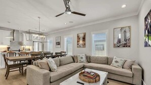 A modern living room with a sectional sofa, dining table, and kitchen area. - Soprano-Private Rooftop-Minutes to Broadway! (Nashville)