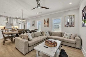 A modern living room with a sectional sofa, dining table, and kitchen area. - Soprano-Private Rooftop-Minutes to Broadway! (Nashville)