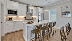 A modern kitchen with white cabinetry, stainless steel appliances, a central island with bar stools, and pendant lighting. - Soprano-Private Rooftop-Minutes to Broadway! (Nashville)