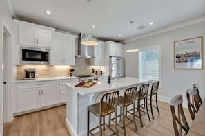 A modern kitchen with white cabinetry, stainless steel appliances, a central island with bar stools, and pendant lighting. - Soprano-Private Rooftop-Minutes to Broadway! (Nashville)