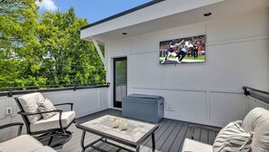 A deck with outdoor seating, a TV mounted on the wall, and a large air conditioning unit. - Alto- Lrg Private Rooftop- Mins to Broadway & 12 S (Nashville)