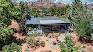 Ein modernes Haus mit einer großen Terrasse, umgeben von einem liebevoll angelegten Garten und Blick auf die Berge.