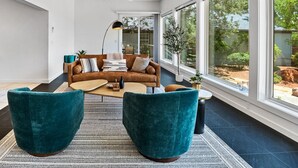 Ein modernes Wohnzimmer mit einem braunen Ledersofa, Türkis-Armstühlen und einem Couchtisch.