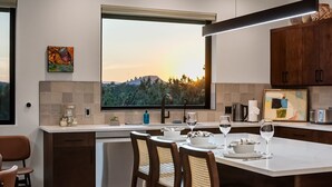 Cozinha moderna com uma janela ampla, eletrodomésticos de aço inoxidável e uma área de jantar com cadeiras de vime.