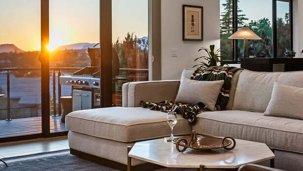 Uma sala de estar moderna com sofá, mesa de centro e vista para uma churrasqueira externa.