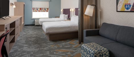 A hotel room with two beds, a desk, a TV, and a couch.