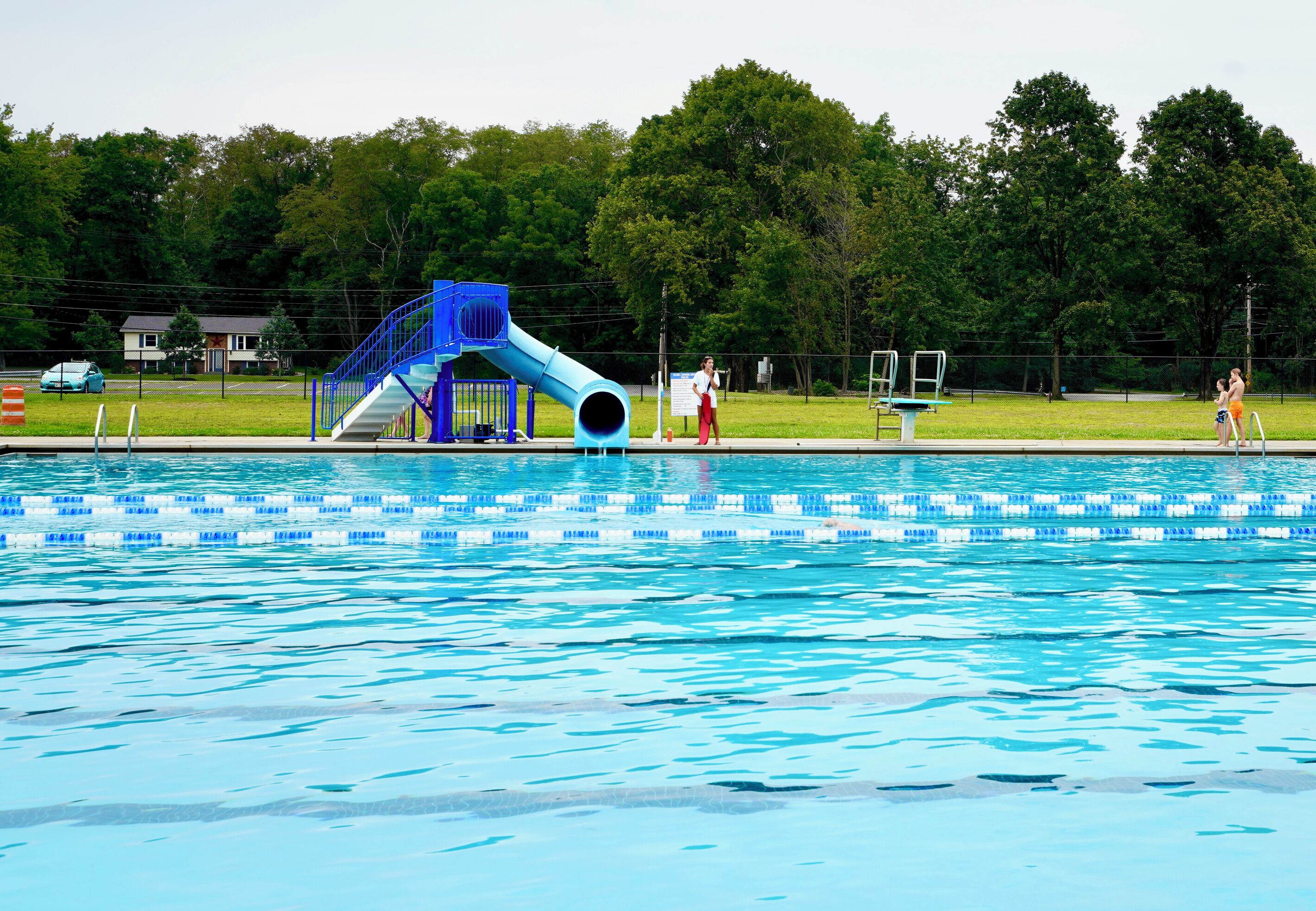 A swimming pool with a blue slide and a diving board.