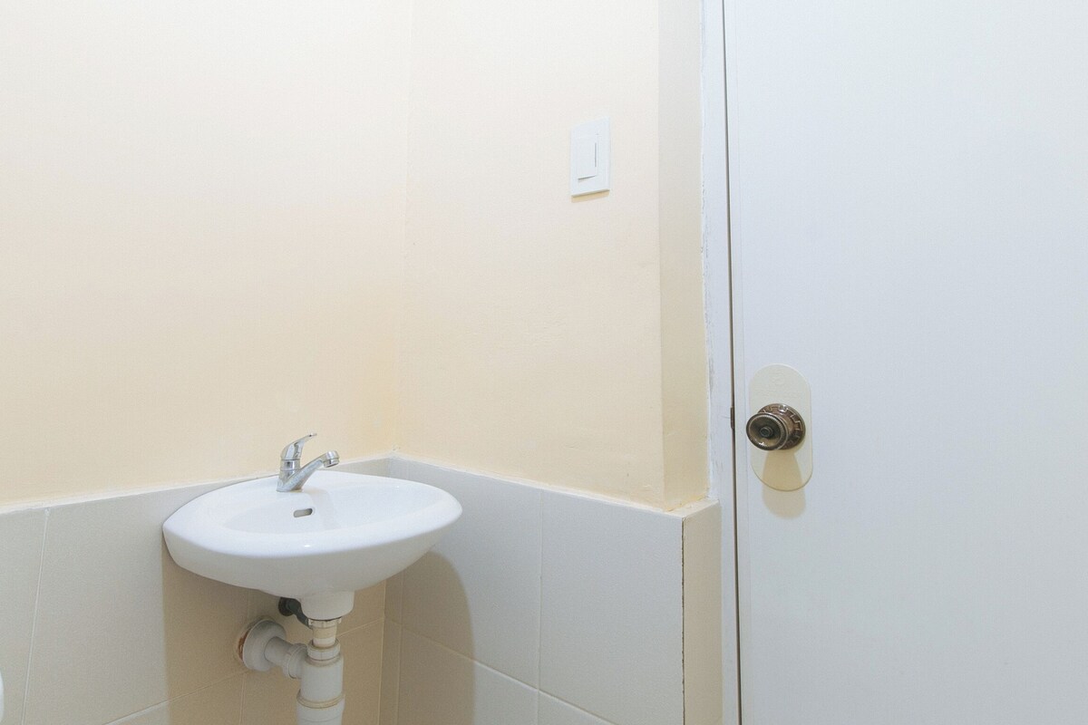 A bathroom with a white sink, a door with a lock, and beige walls.