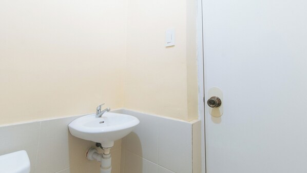 A bathroom with a white sink, a door with a lock, and beige walls.