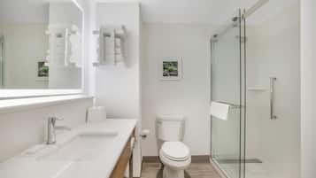 Un bagno moderno con un ampio specchio, due lavabi, un water e una cabina doccia in vetro.