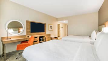 Habitación de hotel con dos camas, un escritorio con silla, un espejo redondo y un televisor.