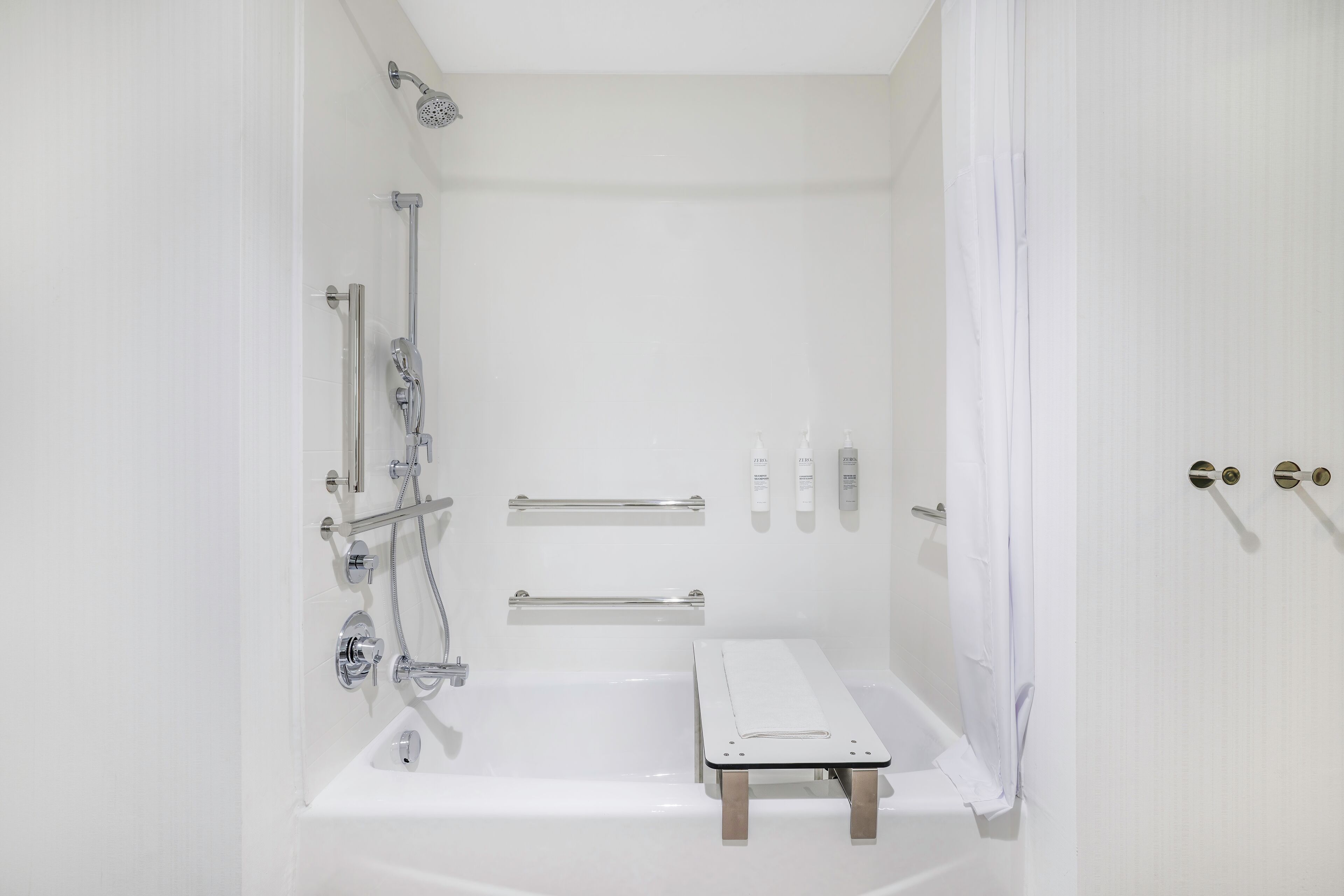 A modern bathroom with a bathtub, shower, and grab bars.