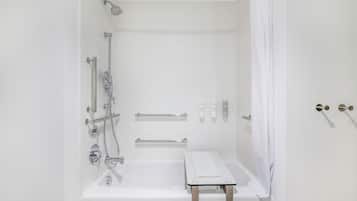 A modern bathroom with a bathtub, shower, and grab bars.
