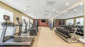 Un gimnasio con cintas de correr, elípticas y una variedad de pesas.