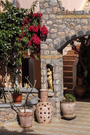 A stone archway with a statue, potted plants, and a tiled floor. - Polydefkis Hotel (Santorini)