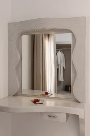 A bathroom vanity with a large mirror, a towel rack, and a small cabinet. - Polydefkis Hotel (Santorini)