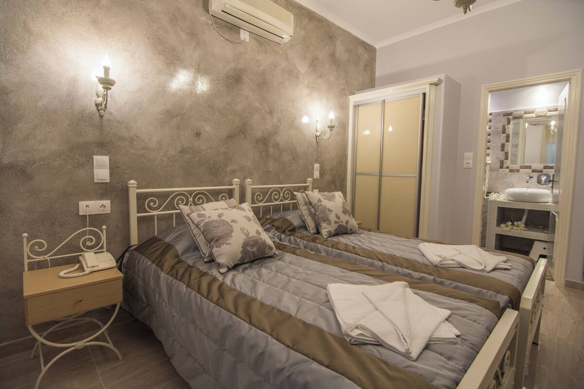 A bedroom with two beds, a bedside table with a phone, and a mirror.