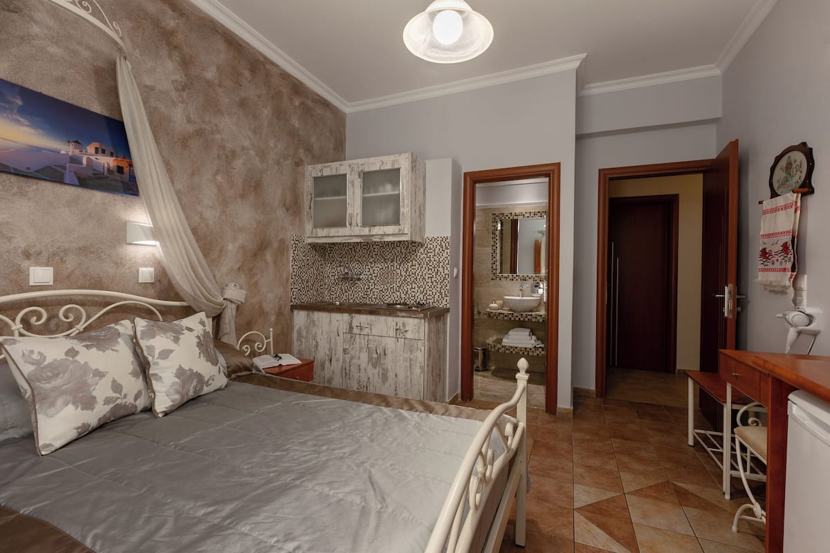 A bedroom with a bed, a vanity with a mirror, a sink, and a small desk.