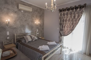 Une chambre à coucher avec un lit, des tables de chevet, un lustre et une fenêtre avec des rideaux.