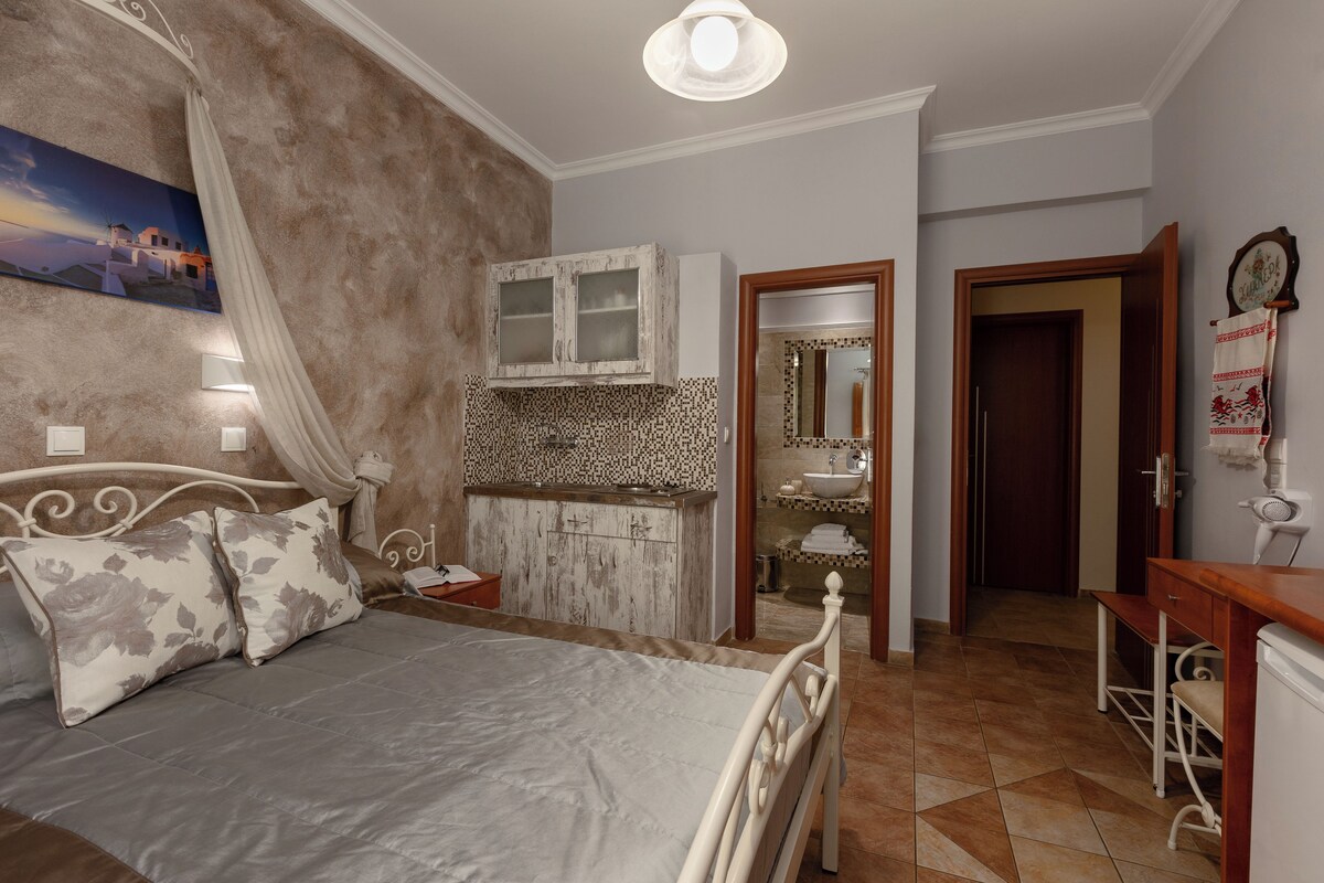 A bedroom with a bed, a vanity with a mirror, and a door leading to another room.