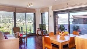 Un espai de estar ampli amb taula de dinar de fusta, seients confortables, televisió de pantalla plana i grans finestres que ofereixen una vista panoràmica.