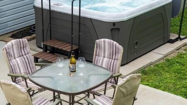 Un bain à remous avec une table et des chaises dans un jardin.