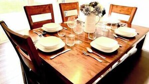 Une table à manger dressée pour quatre personnes, avec des chaises, des assiettes, des verres et des couverts.