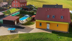 Una zona residencial con una piscina, una casa roja y un edificio amarillo con techo rojo.