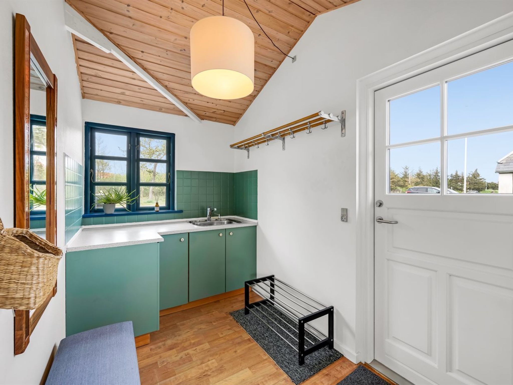 Una cocina moderna con techo de madera, ventana con detalles azules y puerta blanca.