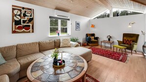 A spacious living area with a high ceiling, a large window, a round coffee table, and a comfortable sofa.