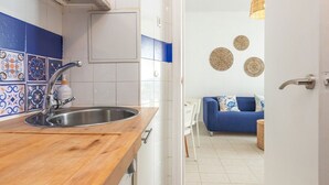 Una cocina moderna con encimera de madera, pileta de acero inoxidable y baldosas decorativas.