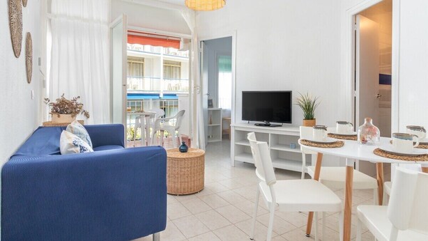 Una sala moderna con sofá, televisión, mesa de comedor y sillas.