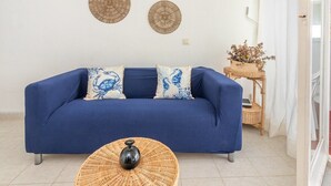 Un sofá azul con cojines estampados, una mesa de centro de mimbre y decoración en la pared.