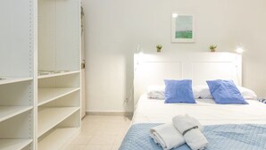 Habitación de hotel con cama, cabecera, estantería y un cuadro colgado en la pared.