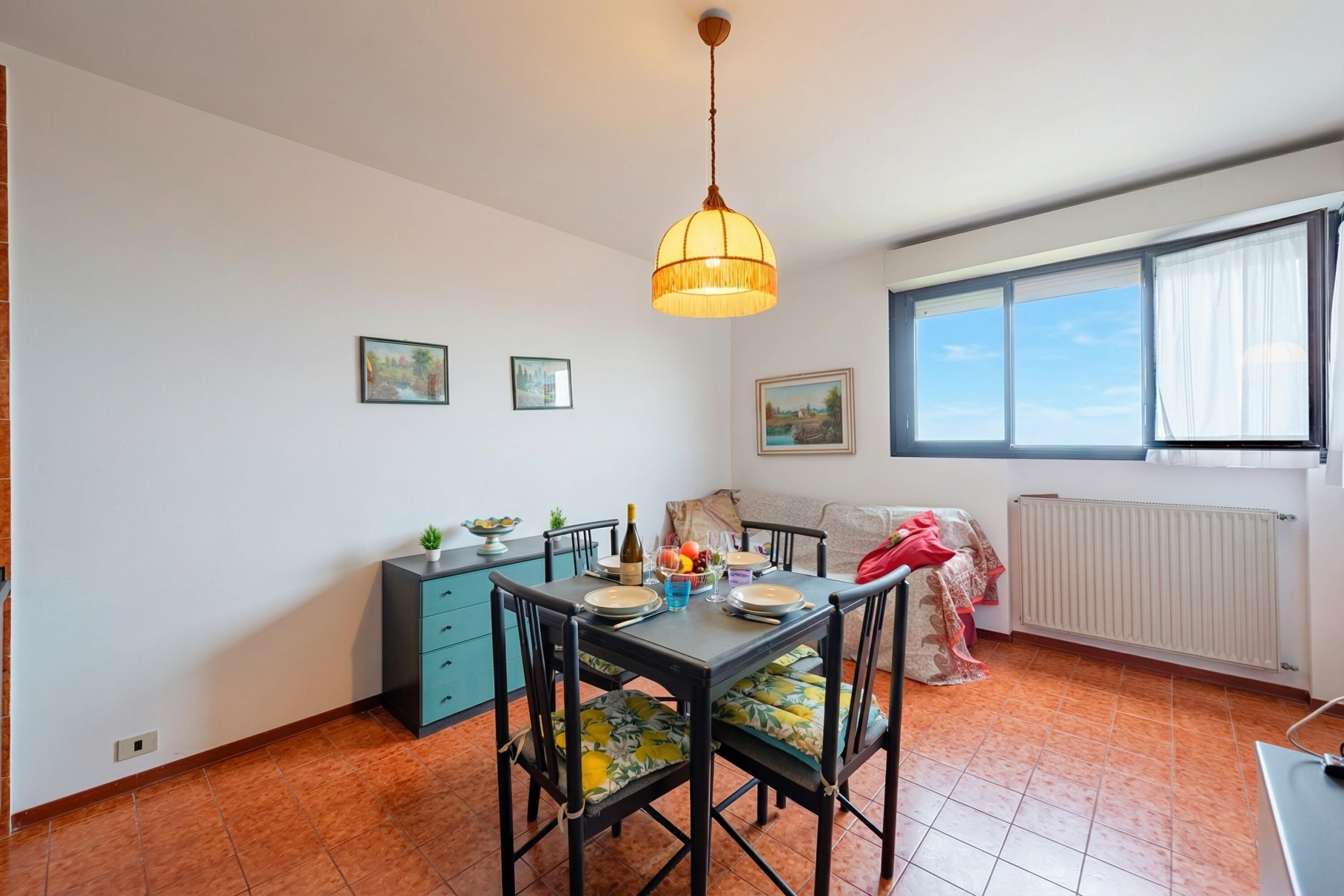 A dining area with a table set for four, a blue cabinet, and a radiator.