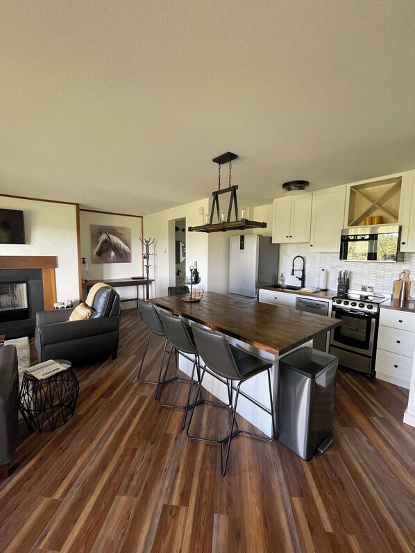 A modern kitchen with a central island, stainless steel appliances, and a dining area with a leather sofa.