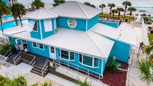 Ein zweistöckiges Gebäude in Blau und Weiß mit Pool und Blick auf den Strand.