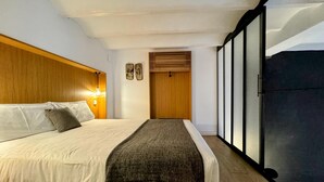 A modern bedroom with a large bed, wooden headboard, and a view of the outdoors through a sliding door. - Urban Elegance Close to the Bullring 2BR · 2BA (Sevilla)