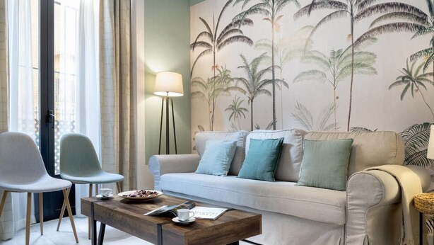 A living room with a sofa, two chairs, a coffee table, and a floor lamp. - Sevillian Charm on Sol street - Comfort and Tradition 5 Min from Las Setas (Sevilla)
