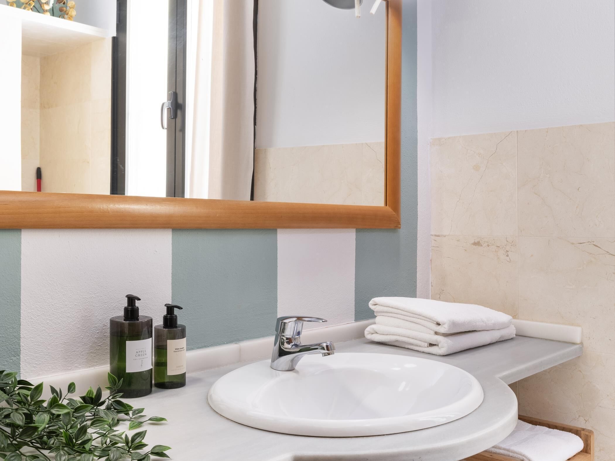 A bathroom with a white sink, a mirror, and a towel rack.