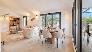 Una sala de estar moderna con comedor, ventanas amplias y una estantería empotrada.