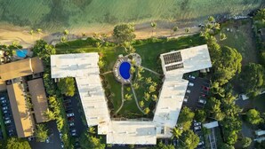 Luchtbeeld van een hotel met een centrale binnenplaats, parkeerplaatsen en omliggend groen.