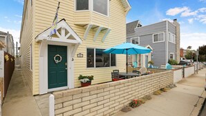 A two-story house with a green door, a blue umbrella, and a brick wall. - AC Family friendly 3 bed/3 bath, Spacious, Comfortable, AC, WiFI, Beach Toys and Parking (Newport Beach)