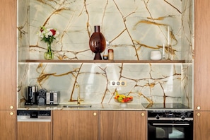 A kitchen with a marble backsplash, wooden cabinets, a coffee maker, a toaster, a fruit bowl, and a Siemens dishwasher.