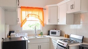 A compact kitchen with white cabinets, a black refrigerator, a microwave, a stove, and a sink. - Hilltop View: Convenient & Peaceful Studio Haven (Cedar Valley Mill Road)